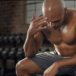 Middle-aged man sitting with low energy before a workout, representing hormone-related fatigue in men over 40