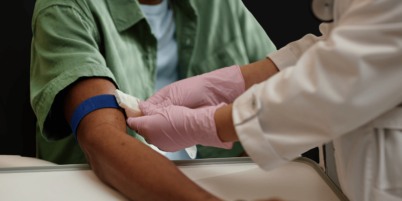 Doctor drawing a patient’s blood for hormone testing to evaluate testosterone, DHEA-S, estradiol, and related markers.