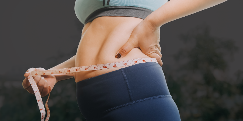 Adult measuring waist circumference to assess why fat loss stops after 40