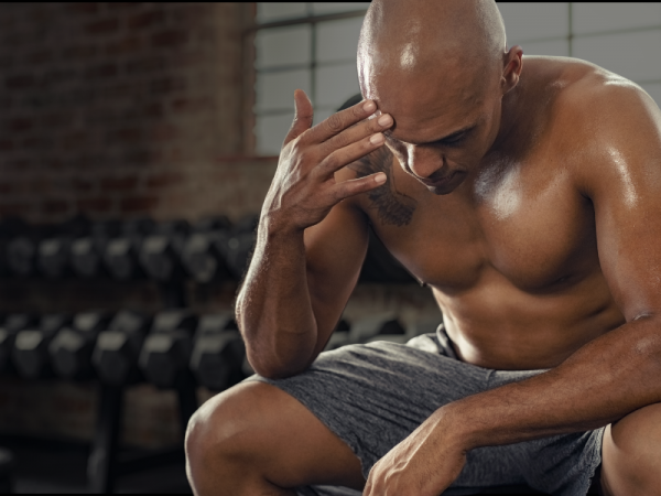 Middle-aged man sitting with low energy before a workout, representing hormone-related fatigue in men over 40